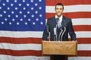 Political candidate at podium by American flag